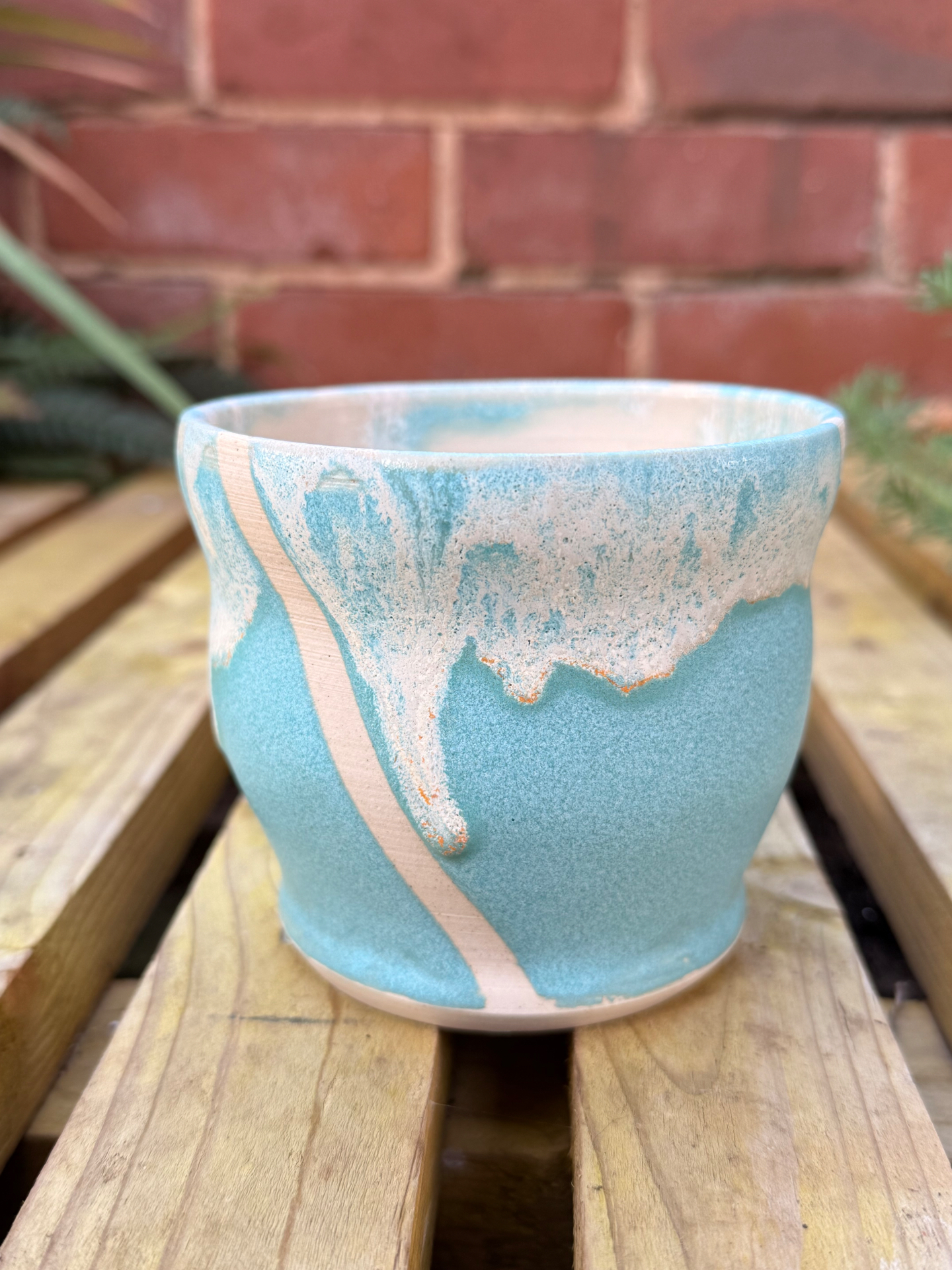 A Turquoise Beach handleless cup — soft sea-blue glaze meeting a foamy white wave