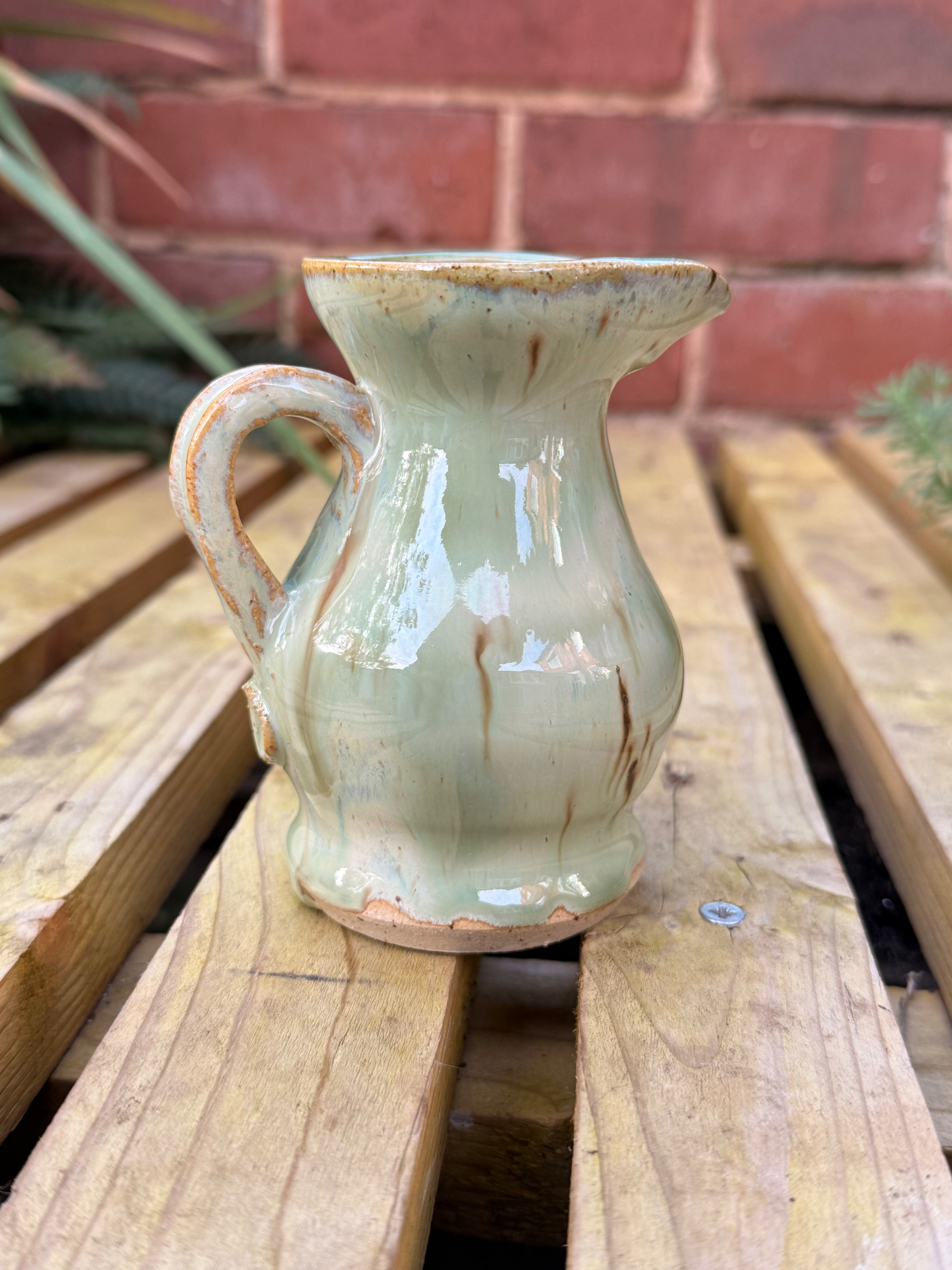 The Small Cream Pourer with its swirled handle, in pale cream glaze with toasty brown drips