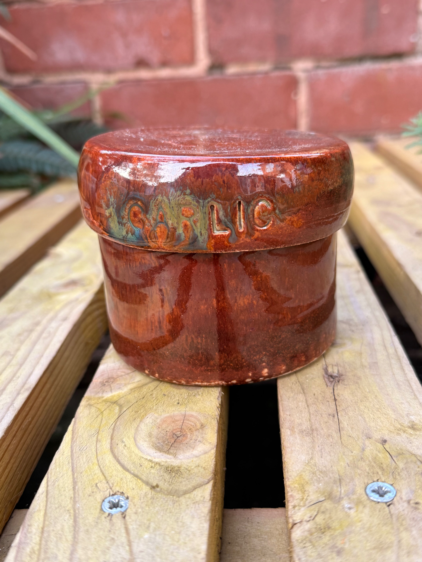 The Garlic Keeper with GARLIC embossed on its lid, in a glossy rust glaze